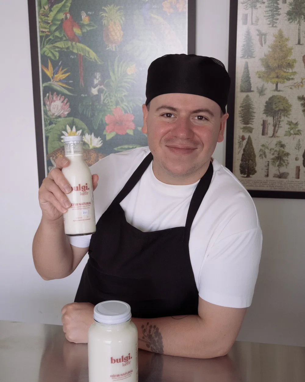 Mario, con mandil, sostiene una botella de kéfir Bulgi en su cocina.