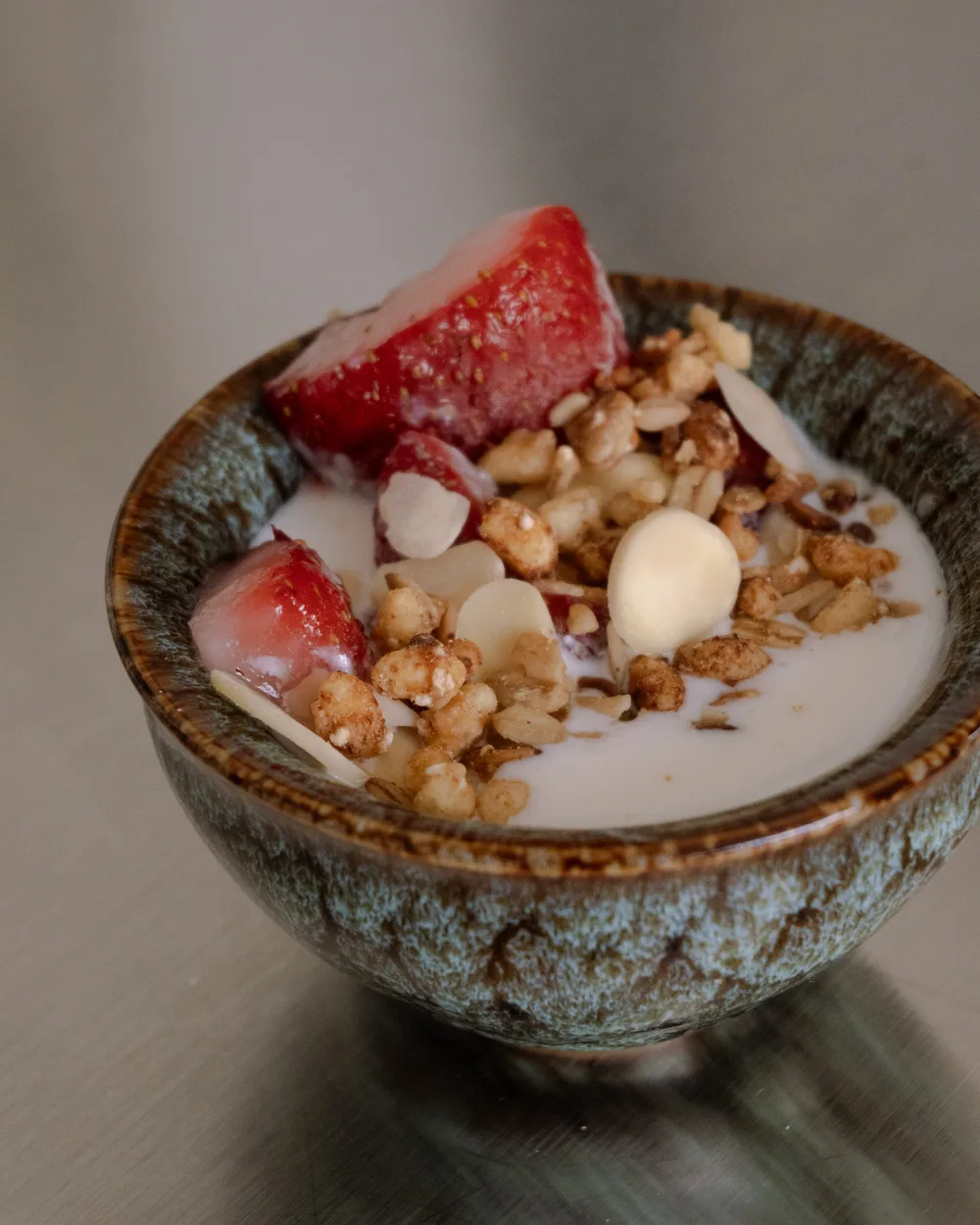 Un tazón de kéfir con fresa, granola y almendras.